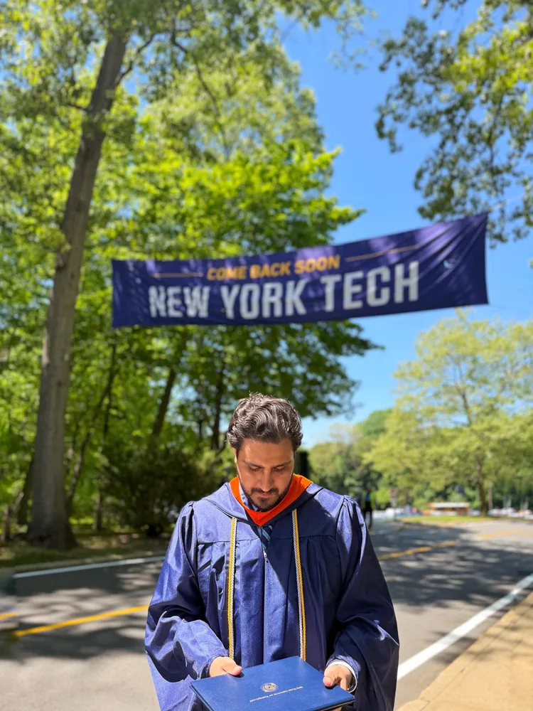 Zulqarnain in regalia under a Come Back Soon New York Tech banner